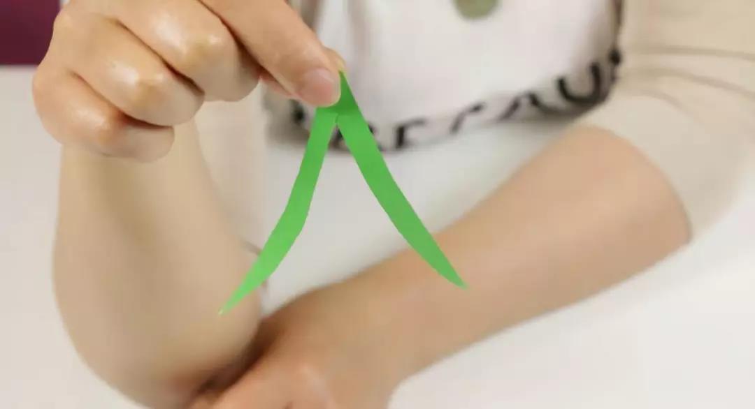 步骤8：在绿色彩纸上用铅笔画出樱桃梗的形状，按照形状剪下来。