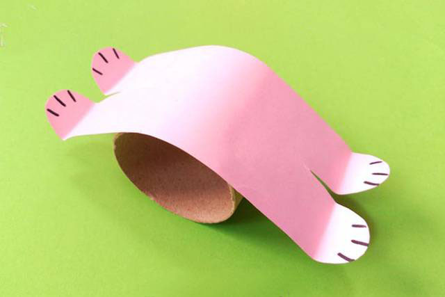 步骤6：将兔子的身体粘在卫生纸筒上，前后脚掌向上折叠一下。
