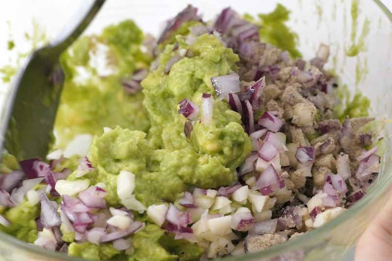 加入柠檬汁、盐、胡椒粉及黑胡椒于牛油果酱中拌混。 