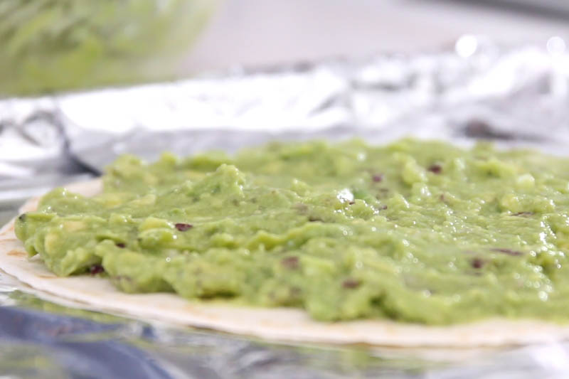 把混好的牛油果酱涂在Tortilla墨西哥薄饼上。 