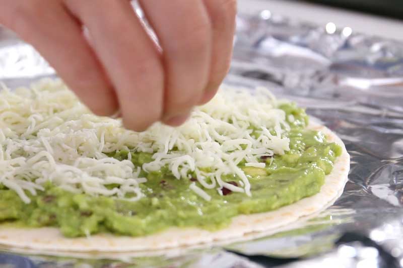 把芝士碎放平均洒于牛油果酱表面。