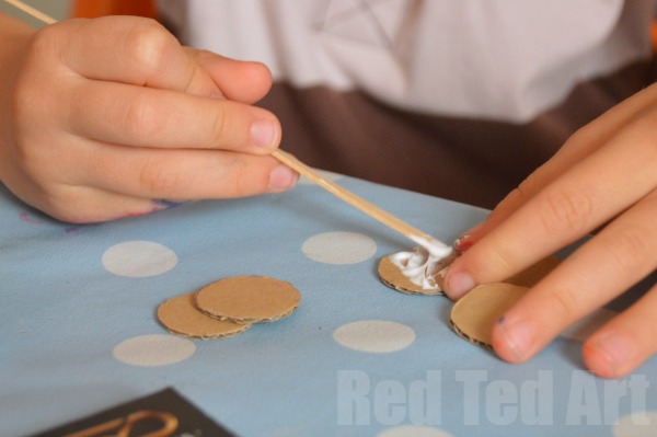 步骤1：剪出6张瓶盖大小的圆形纸板，用胶水将它们粘在一起，作为相机的镜头用。