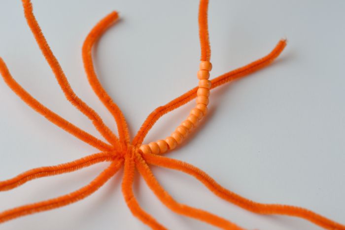 步骤3：在南瓜每只“腿”上窜上橙色的小珠子。