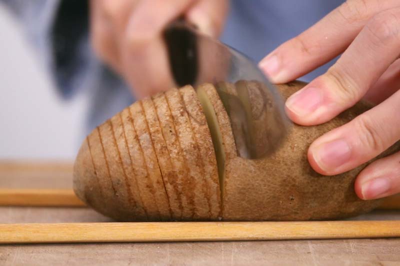 第2步：先把土豆仔刷洗乾净，以筷子垫底把土豆切薄片但不完全切断。这次我们连皮吃，纤维就更加多了。还可以吸收皮里的抗氧化营养素。