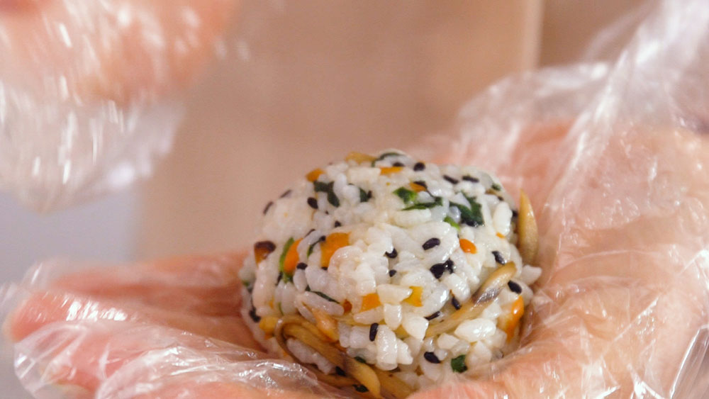 第7步：戴上手套，手上放置适量的拌饭，搓成小饭团。