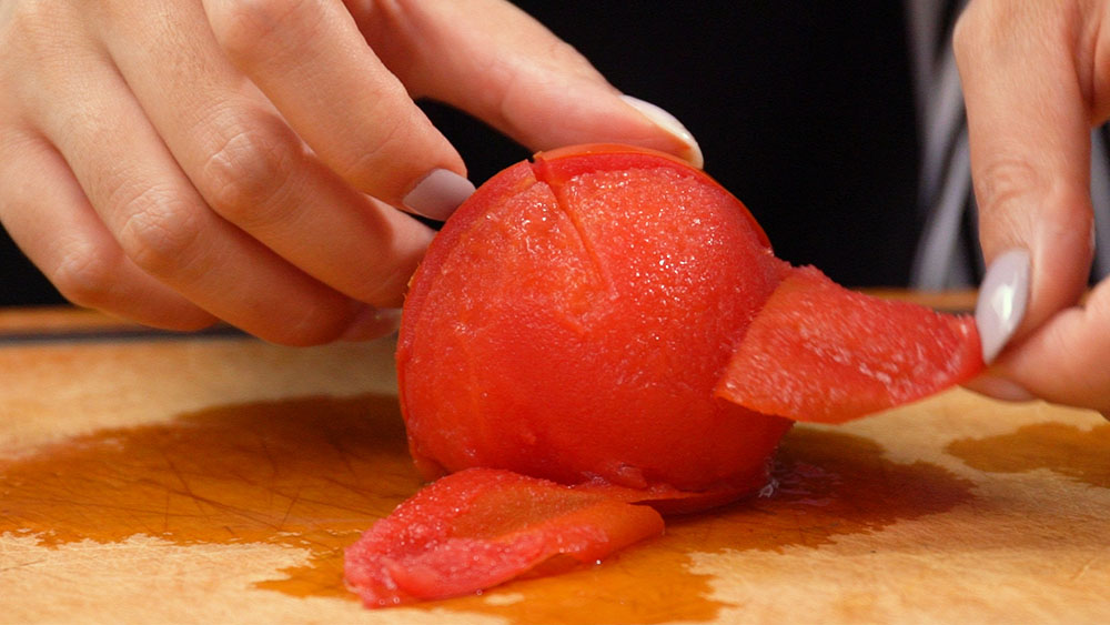 番茄底部用刀划十字，放进滚水里汆烫20秒后，用冷水个冲过，把皮撕下。