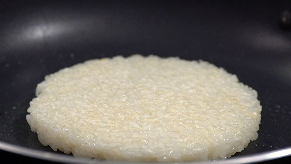 把饭整成10 cm大小的扁圆形状。热锅后倒入少许橄榄油，把米饼两边煎熟。