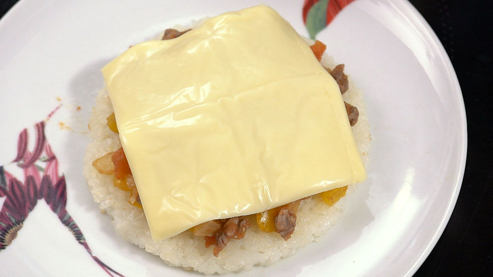 放在米饼上，再将一小片芝士放在最上层，然后将米Pizza放进微波炉加热2至3分鐘即可。