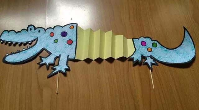 步骤3：将彩色纸折叠作为鳄鱼的身体部分，粘贴后将牙签固定在鳄鱼脚上。 可以拉伸的鳄鱼就完成啦！