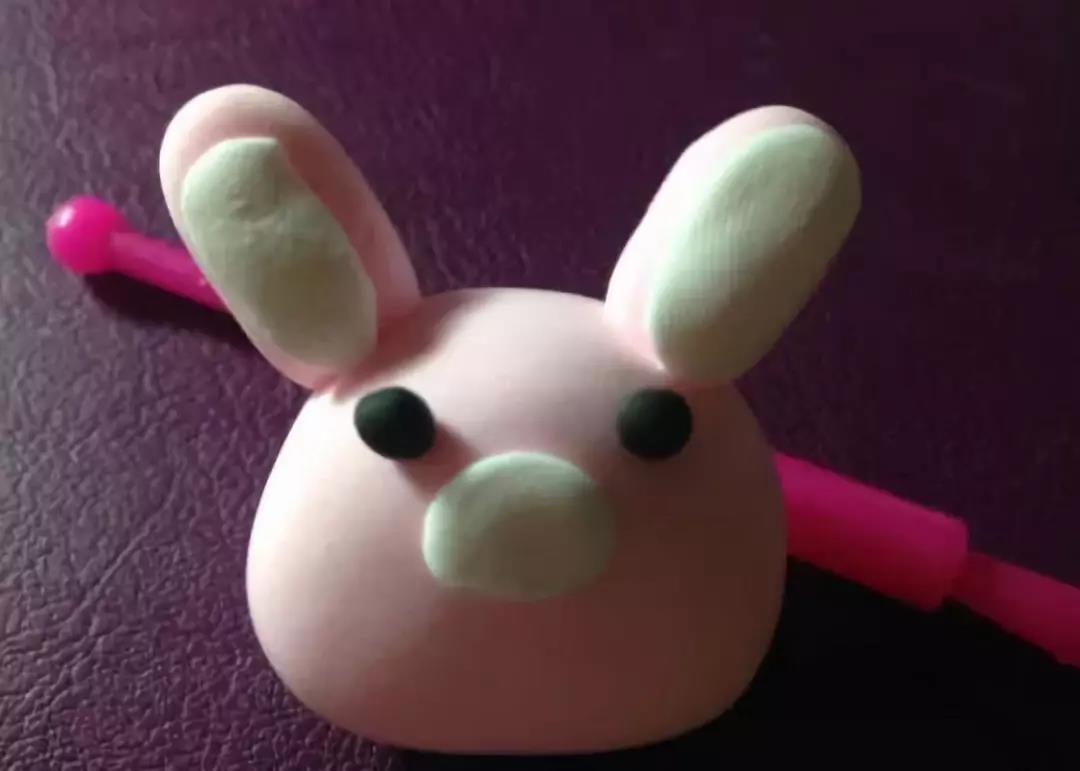 步骤6：用黑色粘土捏出小兔子的两个眼睛，用白色粘土做出兔子的鼻子和两个内耳朵，可以使用辅助工具;
