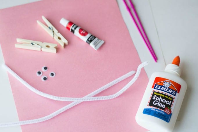 步骤1：准备材料：红色颜料、衣夹、油漆刷、粉色和白色纸张、胶水、剪刀、白色手工毛条、googly眼睛