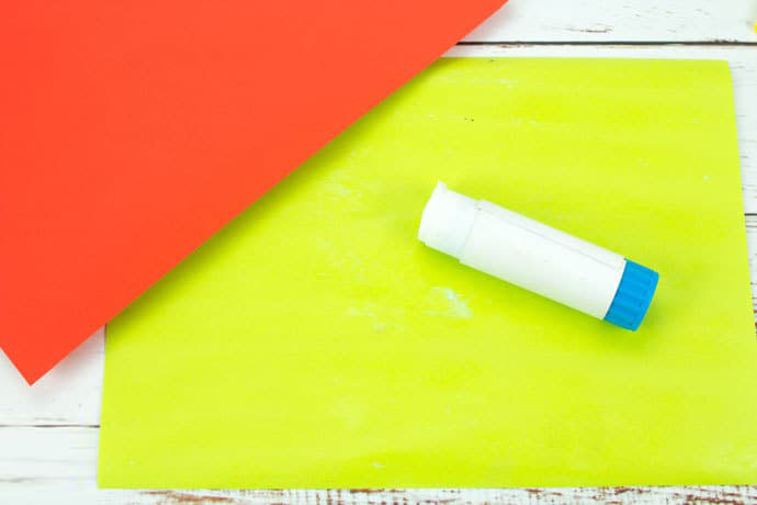 步骤1：准备材料：一面红色另一面绿色的手工纸、胶棒、黑色记号笔、深绿色水彩笔、剪刀、打孔器、开口销。