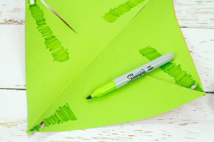 步骤7：在纸张绿色一侧，用深绿色水彩笔画上西瓜皮条纹。