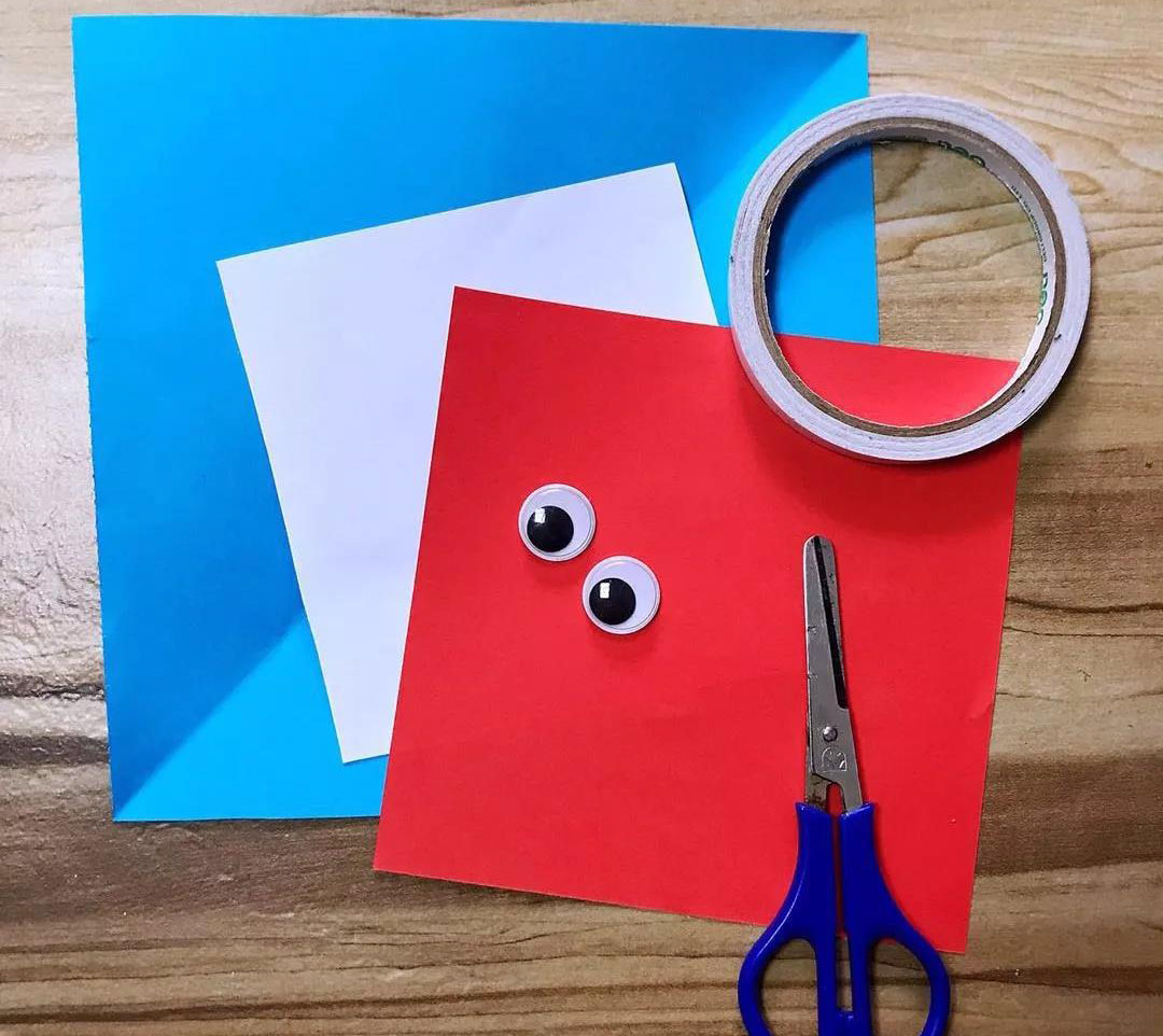 步骤1：材料：白色，蓝色，红色卡纸各一张，双面胶，剪刀，小眼睛（没有的话也可以用白纸代替）