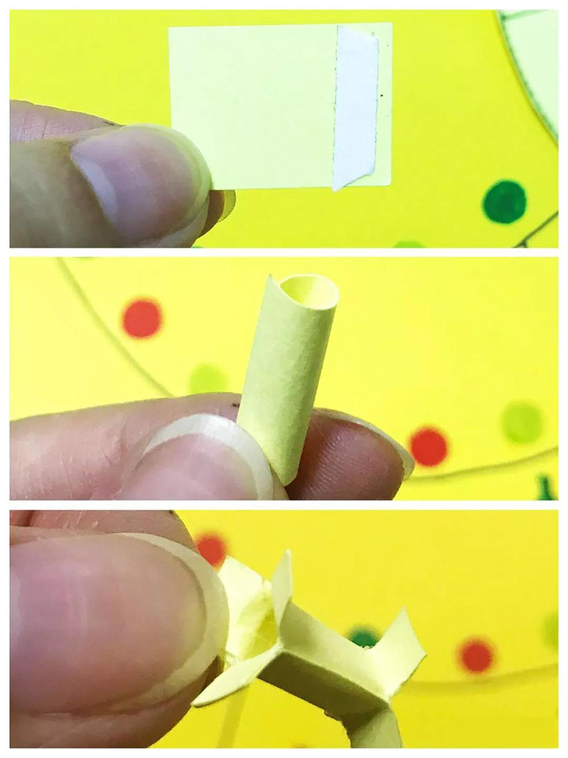 步骤5：这一步很关键，如图我们把小纸片卷成一个筒，两端剪成三块，当转盘的中心轴。