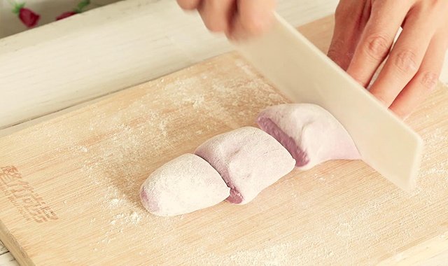 将发酵好的紫薯面团再次揉至光滑，揉成长条状，切成一个个小剂子。