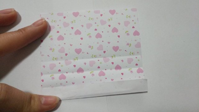 步骤22：然后把纸张底部的纸张沿着折痕一层层卷起来往上折。