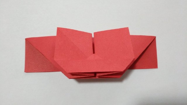 步骤7：接着把上面对折好的小三角的顶端，纸张打开，沿着折痕把三角内折到里面去。