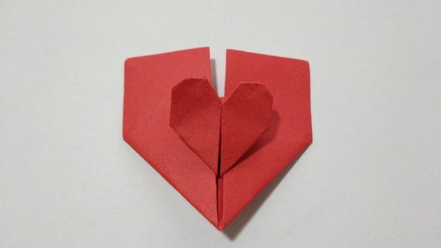 步骤13：接着把中间的小爱心周围折一下，2边的小三角折到里面去，然后把顶端2个小角对折，中间对折，顶端横向对折一下，最后这个中间的小爱心就折好了。