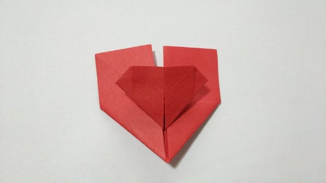 步骤12：然后把中间的纸张的左右2边往中间对折，这样就折出中间的小心形的形状来啦。