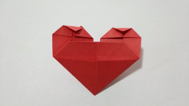 步骤14：最后翻到大爱心的反面，把左右2边顶端的纸先往中间对折，然后再把顶端的小角往下折。
