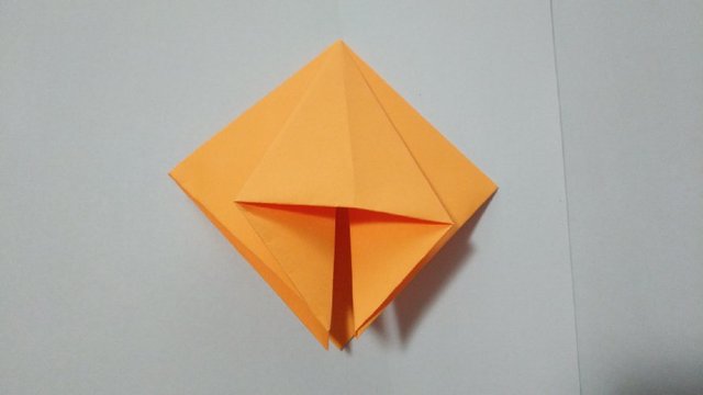 步骤4：然后把折好的正方形的个角从中间往下对折，亚平，压出下图的三角形状来，4条边的4个角一样的折法。