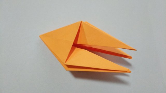 步骤8：然后把折下来的小三角打开，沿着折痕内折到里面去，其他3个角也是一样的内折到纸张里面去。