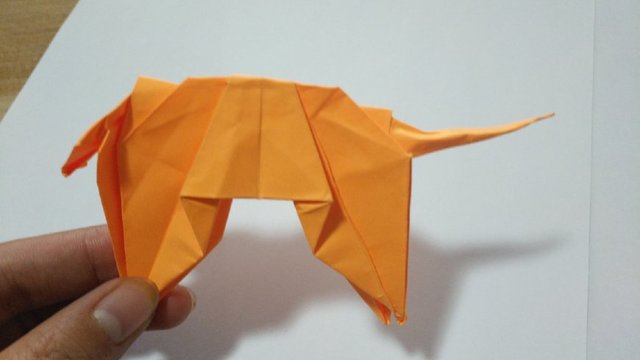 步骤21：然后把纸张往里对折，再往外对折，尾巴底部的纸张沿着折痕往里折，最后把尾巴捏捏，折出老虎的尾巴。
