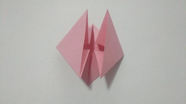 步骤5：然后按照上一步折出来的折痕，把左右2边的纸张往里对折，2边各折出一个三角形，2个三角形是对称的。