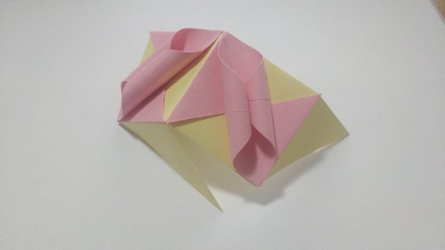 步骤11：这样，折纸花球需要的2个部件就都完成了，接着进入组合花球的步骤，先拿2个为例，把花球的部件的左上角的黄色纸张塞到粉色纸张的左边的小角里。每一个角都这样组合。