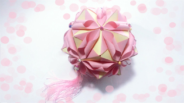 步骤13：折纸花球总共是需要6个面，每个面是5个小部件，最后可以粘上自己喜欢的珠子，然后在最后粘个流苏。