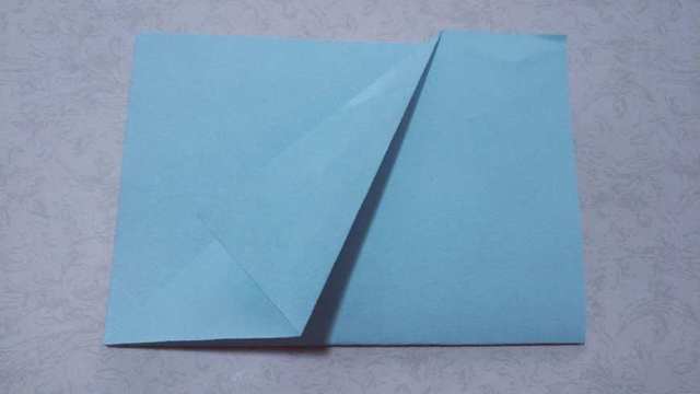 步骤3：然后接着把刚才对折出来的纸张的三角往上对折，对齐纸张的斜边，这样又在表面折出一个三角形来。