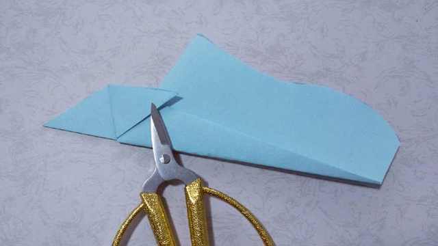 步骤13：裁剪好飞机尾部的样子就是下图，然后接着把左上角的2个小三角往两边对折，折出折痕。