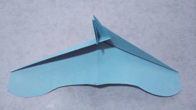 步骤14：再把折好的2个小角展开，把飞机2边纸张平铺在桌面，然后把刚才折的2个小角互相嵌在一起，如下图的样子。