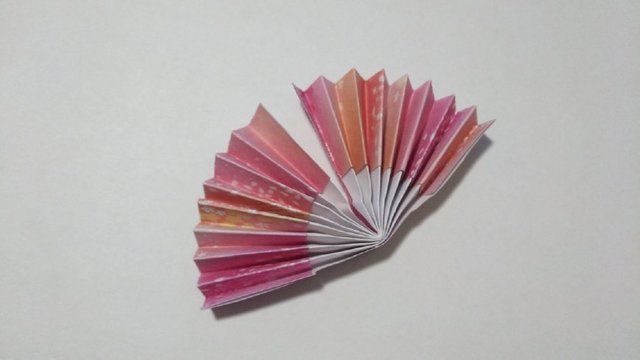 步骤10：然后把纸张从中间对折，把中间涂上胶水，粘在一起，注意扇子底部捏紧一些。