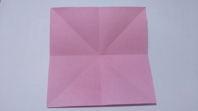 步骤1：准备材料：折纸伞是由2部分组成的，伞面和底下的伞骨。首先我们先来做伞面，纸张尺寸大小为12cm的正方形纸，先对折出基本形状，就是下图的“米”字型。