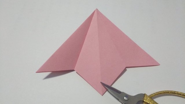 步骤3：接着把其中的一个角从中间往下压平，撑开，压出三角形，注意对齐折痕。