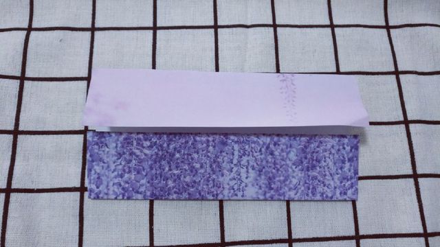 步骤1：准备材料：1张15cm的正方形纸，先把纸张横向对折，中间折出一道折痕，然后把纸张上下2边往中间对折，对齐中间的折痕，我这里直接把最后的图片拍出来了，做法很简单