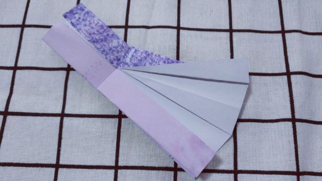 步骤8：然后翻到连衣裙的背面，把右上角的裙子的褶往下压，对折出来，里面的褶也一并对齐。