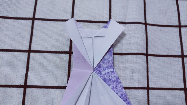 步骤13：最后翻到连衣裙的背面，把前面折好的领子往后折三角，多余的纸张塞到礼服里面去。完美的后背。