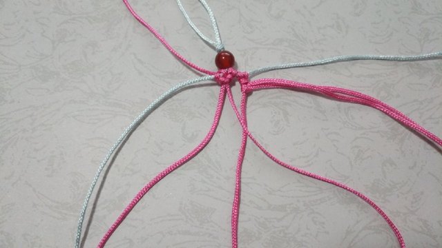 步骤8：然后把雀头结拉到顶上去，接着把左边粉色线的右边那条线搭在右边的线上