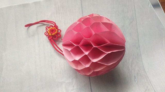 步骤5：最后在最上面涂上胶水，然后把纸张展开，首尾的纸张粘在一起，这样一个蜂窝球灯笼就做好了。