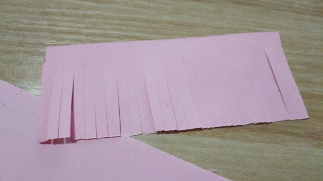 步骤6：最后，再来做一下灯笼穗，再取一张长方形纸条，用剪刀均匀剪一道一道的细长条。