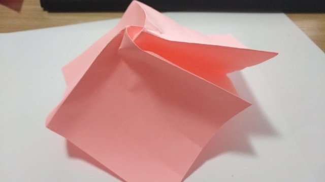 步骤6：然后把玫瑰花的右下角的纸张边缘对齐右上角的纸张边缘然后对折，中间会有一道折痕。