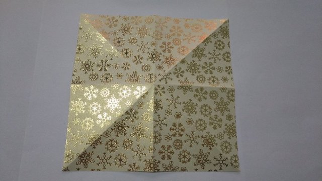 步骤1：准备材料：说起圣诞老人，很多人本能的都是用大红色的纸张来折，这次小编尝试点新风格，用金色的纸来折，金光闪闪的老人是不是更洋气呢？开始来做啦哈，准备15cm的正方形纸，先把纸张米字型对折。