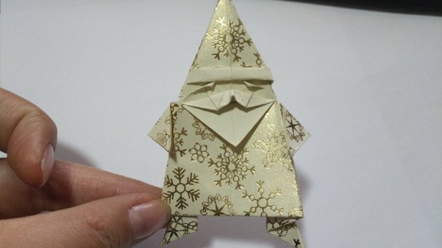 步骤23：然后再把小正方形的上方2个小角往下折，这是圣诞老人的眉毛，然后把头部塞到帽子里面。再把2个胳膊折下来。