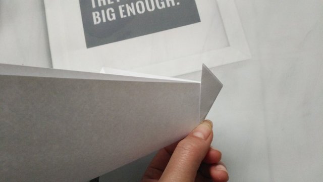 步骤3：然后先拿其中的一个边来，先把纸张对折，然后把小角往左折，折出一个竖着的小角。就是我图上这样，同样的这个折出来的小三角的竖向高度不要太高，2cm到3cm就行。