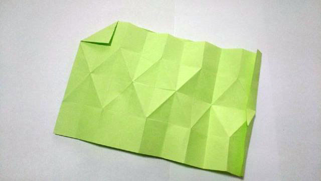 步骤5：上面中间的菱形折痕折痕了之后，接着再来折顶端的波浪线折痕，这里还是同样的，折的时候先把2个格子对折，然后折一个直角。注意这个顶端的三角折痕与下面的那个菱形是不平行的，仔细看一下我拍的图片，就可以明白了。