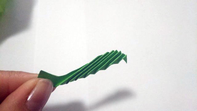 步骤11：叶子形状剪好了之后，把纸张对折出一道一道的折痕，就像风琴褶一样。这样最后做出来的叶子才会有立体感。