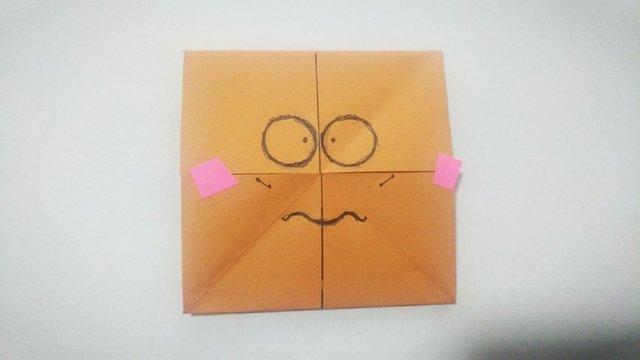 步骤9：上面那一面画好纸张，把纸张上面的往下翻折，下面的对应往上面翻，这样又会翻出新的一面来，然后再画上自己喜欢的表情包，小编今天有点小郁闷，所以画了一个小委屈。